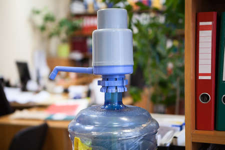 Water dispenser bottle with plastic hand pump standing in office roomの写真素材