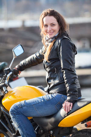 Attractive Caucasian woman with her motorcycle, looking at cameraの写真素材