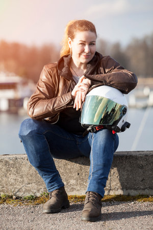 Smiling and happy Caucasian woman with her crash helmet, looking at cameraの写真素材