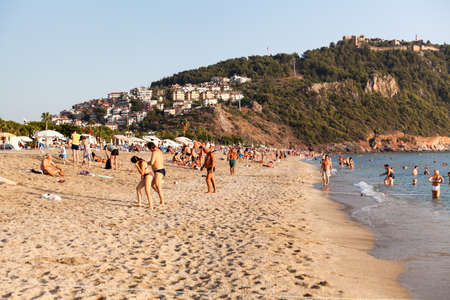Alanya, Turkey-circa Oct, 2020: Adults and children rest on the Kleopatra beach. It is famous sandy beach close to mountain with the Alanya castle. The Mediterranean seaのeditorial素材