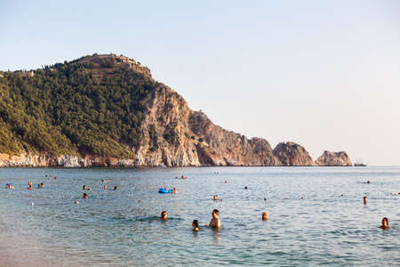 Alanya, Turkey-circa Oct, 2020: The Kleopatra beach during Covid-19 pandemic. Vacationers sunbathe and swim at resort season. It is popular sandy beach close to mountain with the Alanya castleのeditorial素材