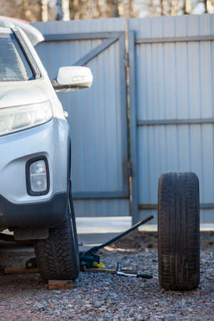 Suv standing on jack-screw for a snow tire removing, summer wheel is ready to install