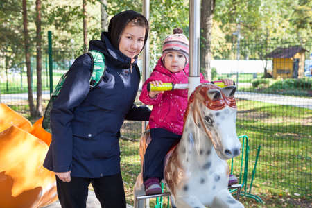 Teenage and child sisters with different ages walking together, gilr cares about little kid, two personsの写真素材