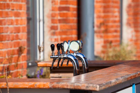 Two steel chrome beer taps are on bar counter, outdoorの写真素材