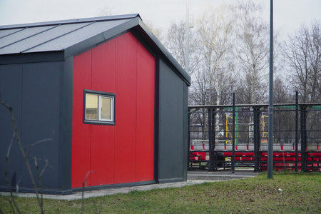 Striking minimalist red metal-clad industrial building with clean lines and large dark windows standing in sharp contrast against bare trees and natural surroundings in Scandinavian style architectureの写真素材