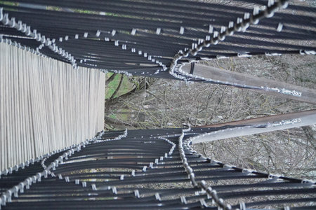 view from below wooden suspension bridge with thick ropes and planks dramatic perspective adventure travel nature outdoor hiking structureの写真素材