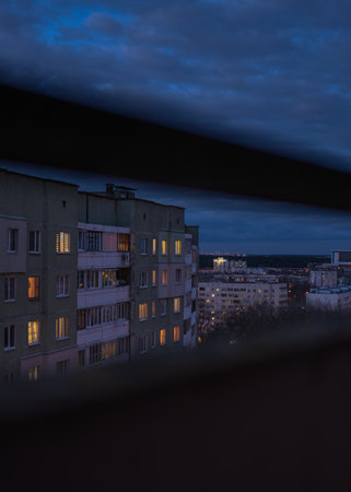 Night view in Minsk Belarus shows Soviet era apartment facades with warm windows, dark railings in...