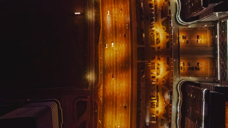 Top down view of a well lit street in Minsk, Belarus, with orange streetlights, modern curved buildings, and symmetrical roads and parking areas.の写真素材