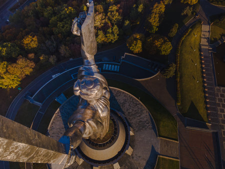 Aerial perspective of the Motherland Monument in Kyiv, Ukraine, showcasing the raised shield with the Ukrainian coat of arms and autumnal surroundings.の写真素材