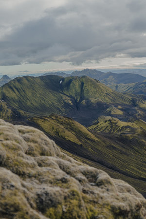 Rugged moss covered mountains and valleys in Iceland with textured rock formations in the foreground and peaks extending into the distance.の写真素材