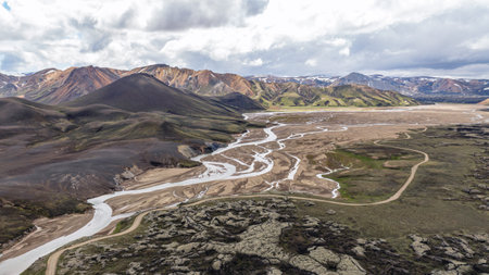 Aerial perspective of Landmannalaugar, Iceland, featuring colorful rhyolite hills, braided rivers, volcanic rock formations, and snow capped peaks.の写真素材
