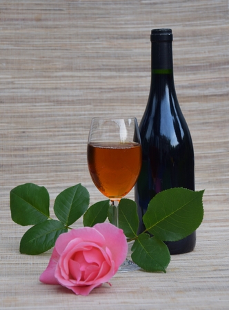 Wineglass and wine bottle on a table with a red roseの写真素材