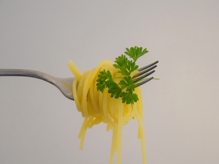 Spaghetti and parsley on a silver forkの写真素材