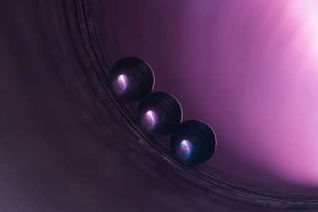 Three transparent small ball on the surface inside the pipe, lit and colored with bright lightの写真素材