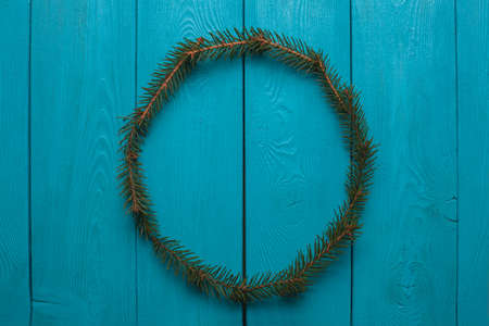 Fluffy wreath. A wreath from Christmas tree branches on wooden Board. A wreath of fir. New year symbol on blue background.の写真素材