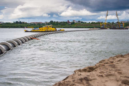 Orange river vessel working on the river. Rain clouds. The Ob river in Siberia in cloudy weather. The construction of a sewer dyuker through the river.の写真素材