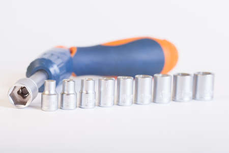 Screwdriver with adapter. A set of heads and a screwdriver on a light background.