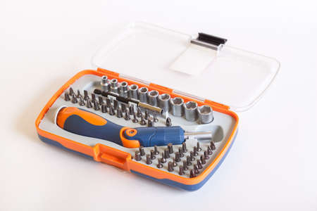 Packing set heads under the nuts on a light background. Metal bits and flat-head screwdriver. Nozzles and adapters for a drill.の写真素材