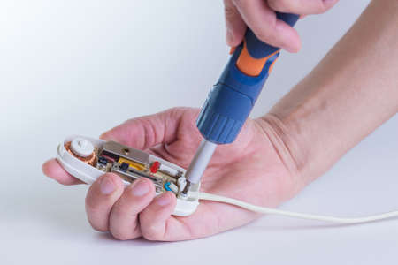 Male hands on white background holding a screwdriver. Repair of household appliances. The provision of services for the repair of electrical equipment.の写真素材