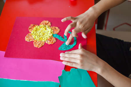 Children's hands make the application. The boy's hands close up make a flower out of paper. Children's entertainment. The creativity of paper.の写真素材