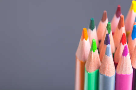 The sharp tips of the pencils. Bright colored pencils. Colored pencils on grey background with selective focusの写真素材