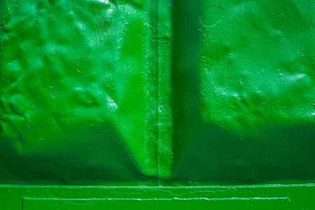 Stamped metal surface. The green background. Painted metal surface. The surface of the train as a background element. Metal painted green. Iron plates welded togetherの写真素材