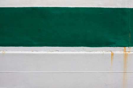 Green stripe on a white background. Paint smudges on the surface. White rusty background. Painted metal surface. The surface of the train as a background element. Metal painted in white and green.の写真素材