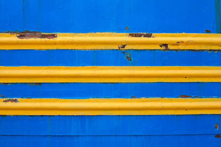 Yellow stripes on blue background. Blue background. Painted metal surface. Metal painted in blue color. Parallel horizontal linesの写真素材