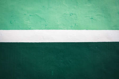 White stripe on green background. Paint smudges on the surface. Painted metal surface. The surface...