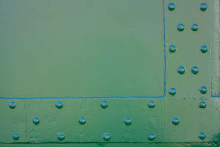 Painted metal surface. Metal surface connected by rivets. Metal painted green. For background on advertisingの写真素材