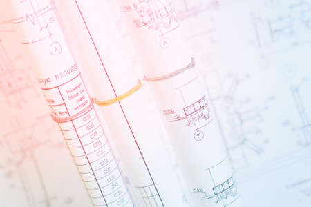 Rolls of drawings. Selective focus on working drawings. Bright pink-and-blue light on the desktop construction engineerの写真素材