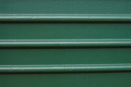 Paint smudges on the surface. The green background. Painted metal surface. Metal painted green. Parallel horizontal linesの写真素材
