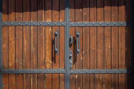 Wooden gates brown closed. The metal elements on wooden structures.