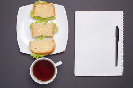 Food for raising motivation. A platter of sandwiches standing on the dark surface. Mug of tea next to a plate of sandwiches. Breakfast student. Place for Your textの写真素材