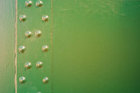 Metal surface connected by rivets. Metal painted green. For background on advertisingの写真素材