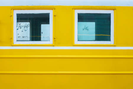 Window on the yellow surface of a passenger train. White lines on a yellow background. Place for...