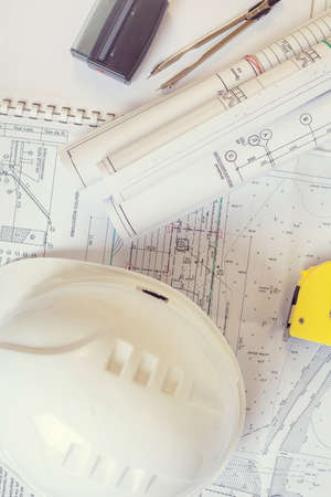 Accessories construction engineer. White safety helmet lies on the drawings. Coils projects near the...