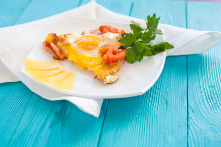 Chicken-fried eggs with tomatoes in white plate and decorated with greens. Cheese cut into slices on the plate.
の写真素材