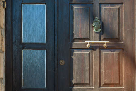 The wooden surface is brown. Door handle made of brass on the wooden door. Light and shadow on the wood material. Corrugated glass in the door.の写真素材