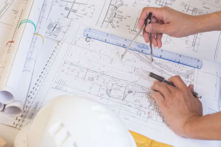 Workplace designer in construction. The hand of the engineer to keep the compass. A man works with drawings.の写真素材