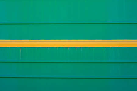 Green background. The yellow line on a green background. Metal painted in green and yellow. Horizontal parallel linesの写真素材