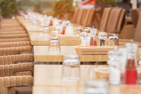 The interior of the restaurant in the open air. Empty tables of street cafe. Wicker furniture in the tavern on the street.の写真素材