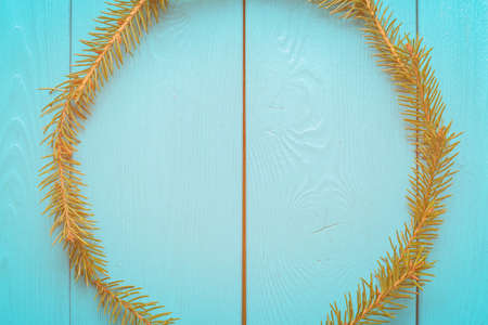 Fluffy wreath. A wreath from Christmas tree branches on wooden Board. A wreath of fir. New year symbol on blue background. Lighting a bright flash. A ray of light on a blue backgroundの写真素材