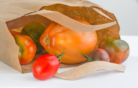Several tomato of different grades near a paper packageの写真素材