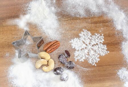 Snowflake from flour, nuts, a form for cookies, flour on a wooden boardの写真素材