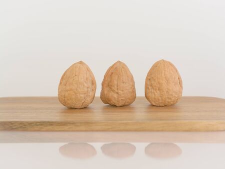 Three walnuts on a wooden cutting board
