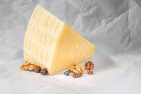 Piece of cheese, nuts and dried fruits on a light backgroundの写真素材