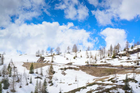 Spring view of the sky with clouds and hills with snowの写真素材