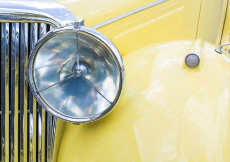 Background with headlight of a yellow non-modern car