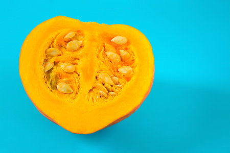 Half of an orange pumpkin with seeds on a turquoise backgroundの写真素材